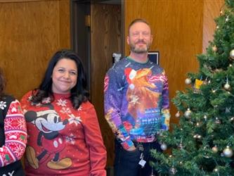 front staff by xmas tree wearing ugly sweaters